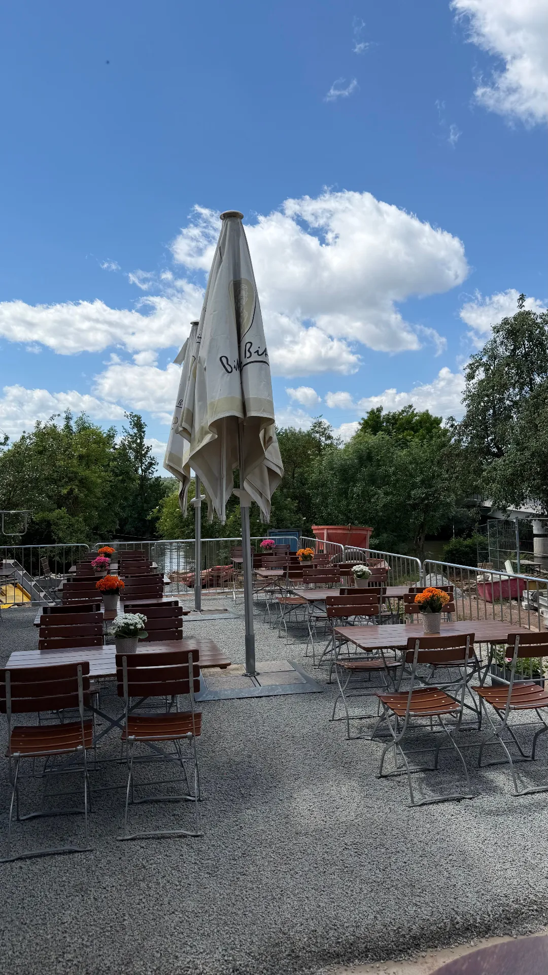 Aktueller Biergarten an der Regnitz mit Sonnenschirm, Biergartentischen und Blumenschmuck