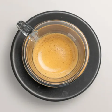 Frisch gebrühter Espresso in einer Glastasse auf schwarzem Teller